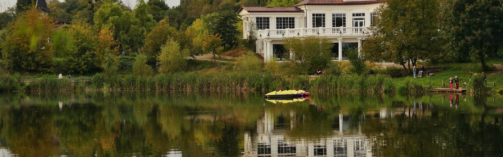 a house sitting on top of a lush green hillside next to a lake