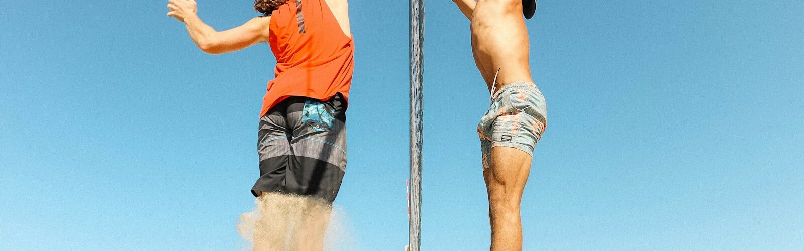 man in orange t-shirt and blue denim shorts holding silver pole during daytime